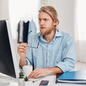 serious-concentrated-pensive-male-businessman-blue-shirt-holds-spectacles-hand-works-computer-thinks-about-financial-report-bearded-manager-freelancer-drinks-coffee-generates-ideas.jpg